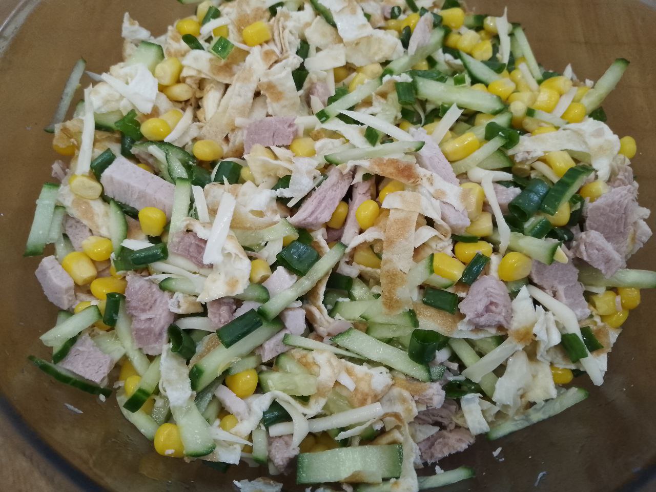Салат вкусный и сытный из мяса, огурцов и яичных блинов: Соединяем мясо, сыр, огурцы, кукурузу, яичные блины и зеленый лук, соль по вкусу, перемешиваем.