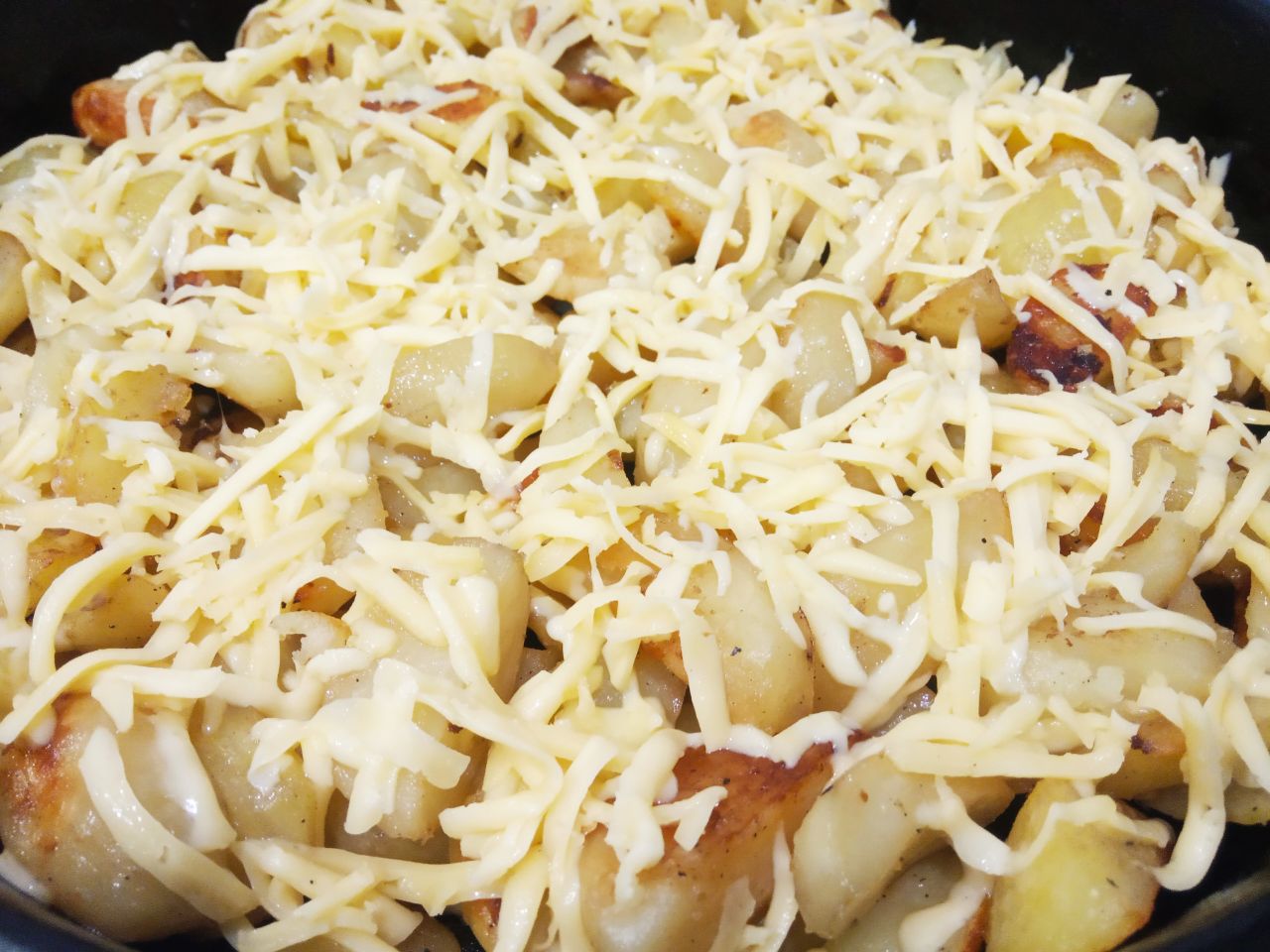 Картофель запеченный с сыром и сливочным маслом: Когда картофель станет мягким и слегка с корочкой, посыпаем тертым сыром.