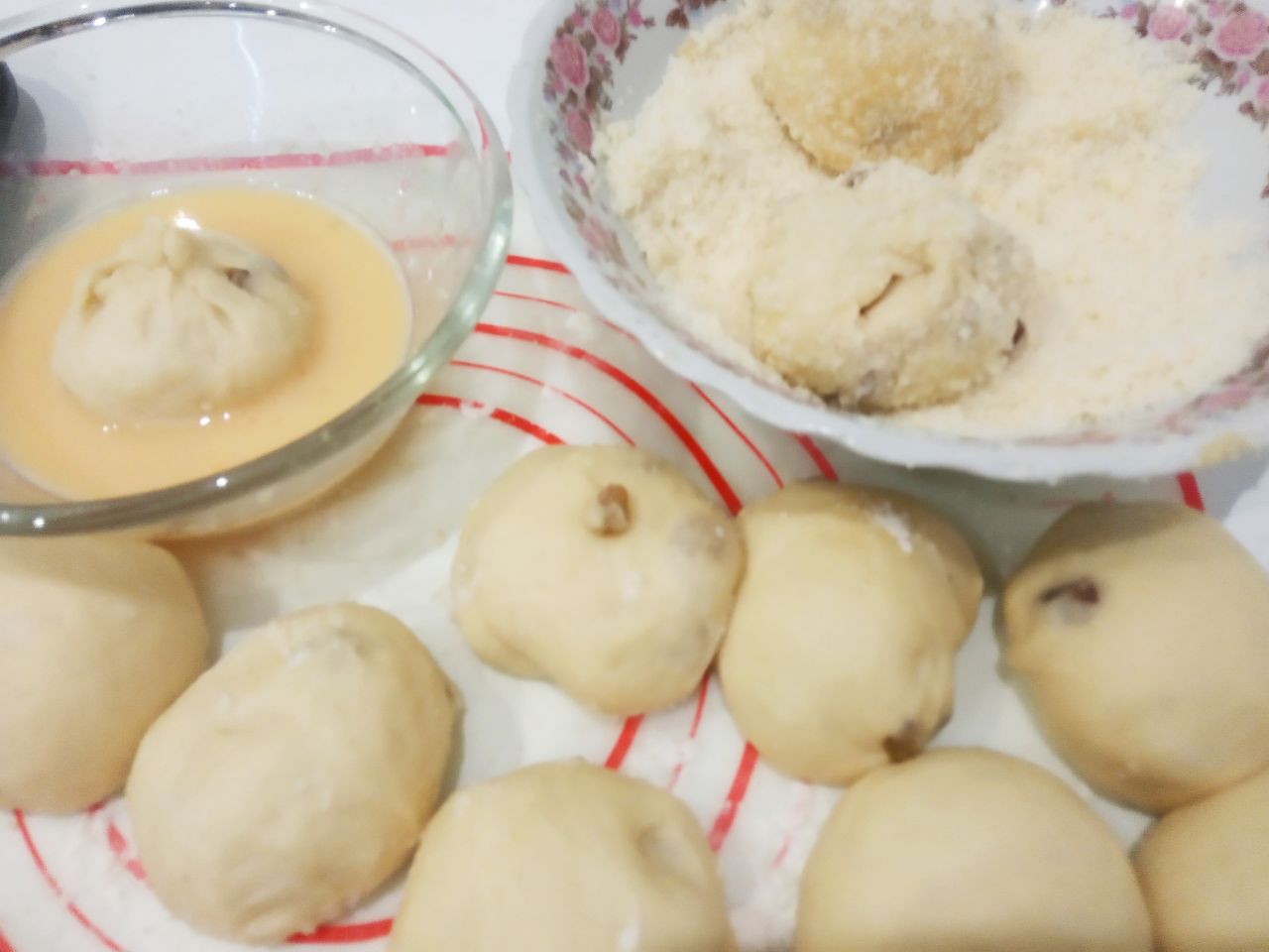 Булочки с изюмом в мучной крошке, воздушные и вкусные: Колобки окунаем во взбитые яйца, придерживая за край колобка, затем хорошо обваливаем в мучной крошке.