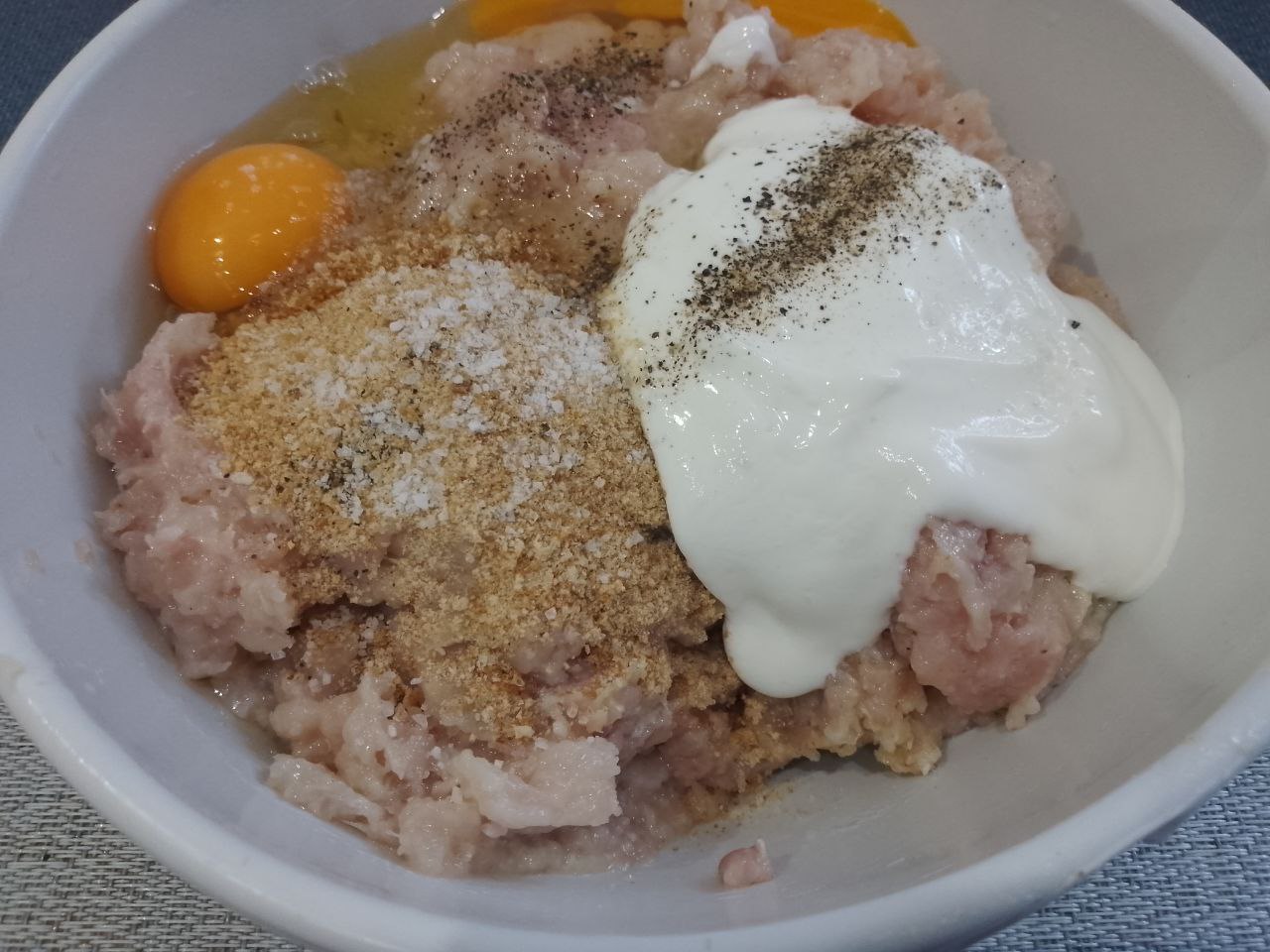 Котлеты из куриного мяса в яичном кляре и панировочных сухарях: В большой миске соединяем фарш, яйца, сметану, панировочные сухари, соль и перец.