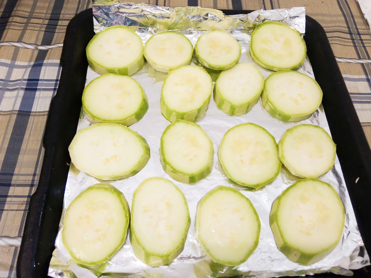 Вкусная закуска из кабачков с фаршем и сыром: Противень застилаем пергаментом или смазываем жиром и выкладываем кабачки.