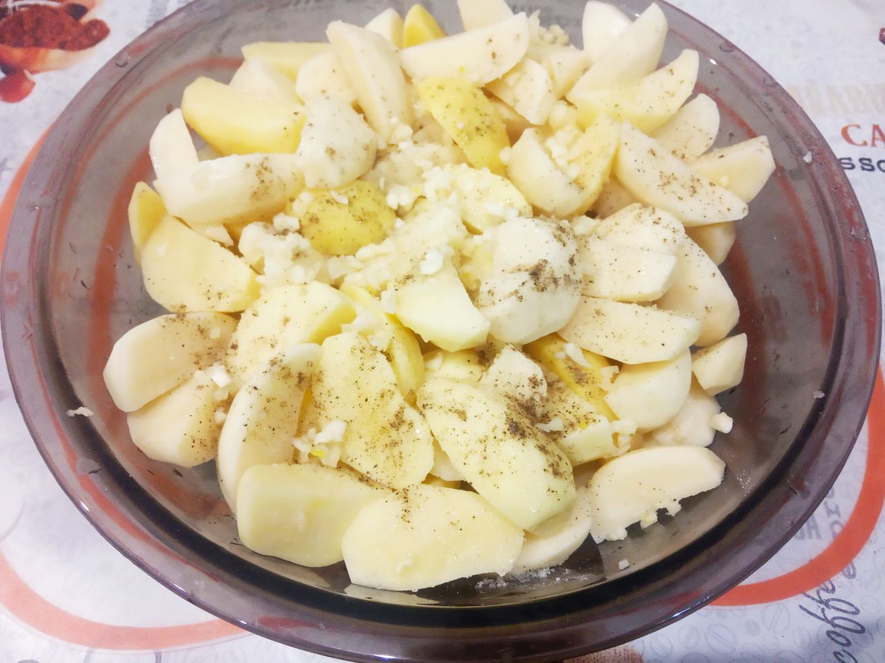 Картофель запеченный с сыром и сливочным маслом: Картофель посыпаем солью, перцем молотым, добавляем чеснок, растительное масло и перемешиваем.