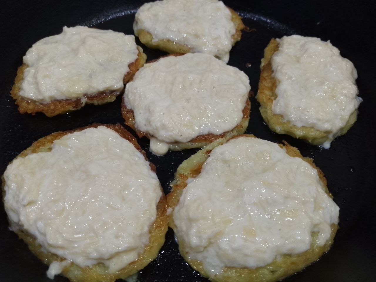 Драники с сыром, яйцом и сметаной: Сковороду накрываем крышкой и обжариваем пока драники не обжарятся до золотистого цвета.