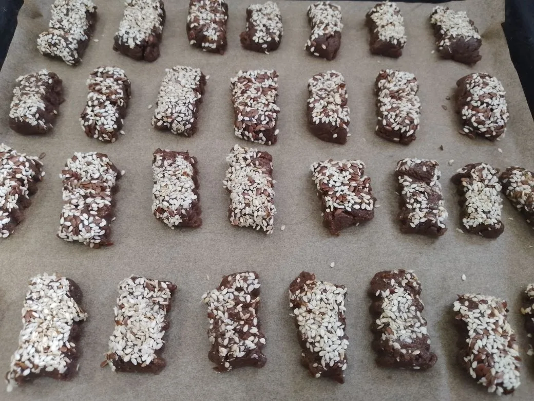 Шоколадное песочное печенье с кунжутом и кокосовой стружкой: Противень покрываем пергаментной бумагой и раскладываем печенье.