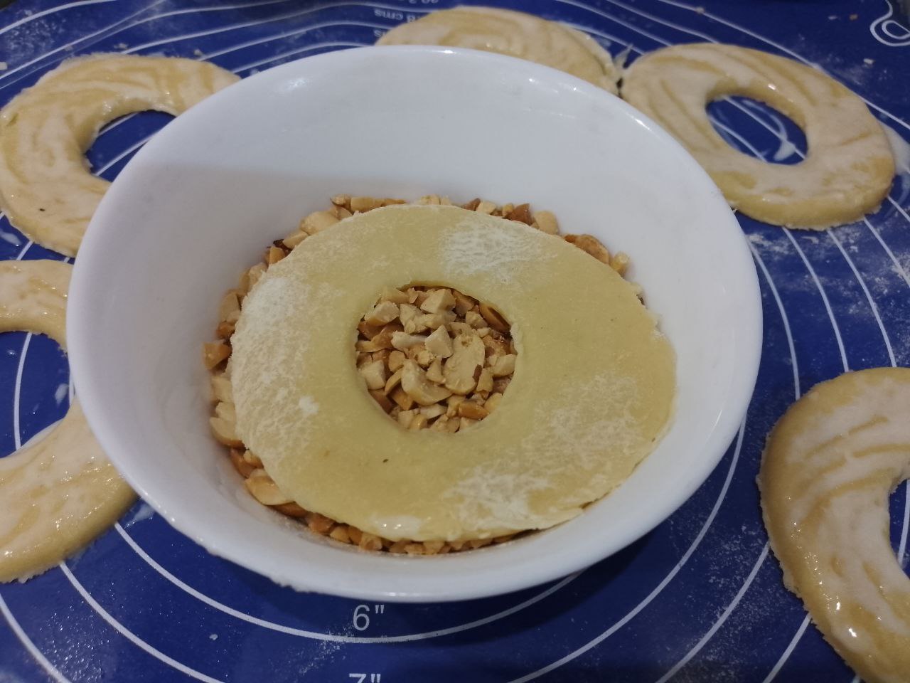 Песочные и рассыпчатые ореховые кольца: Колечки окунаем в измельченные орехи и укладываем на противень.