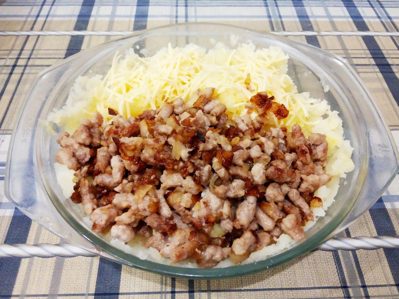 Картофель фаршированный начинкой и запеченный в духовке: Картофель тщательно разминаем толкушкой. Выкладываем обжаренный фарш и хорошо размешиваем.