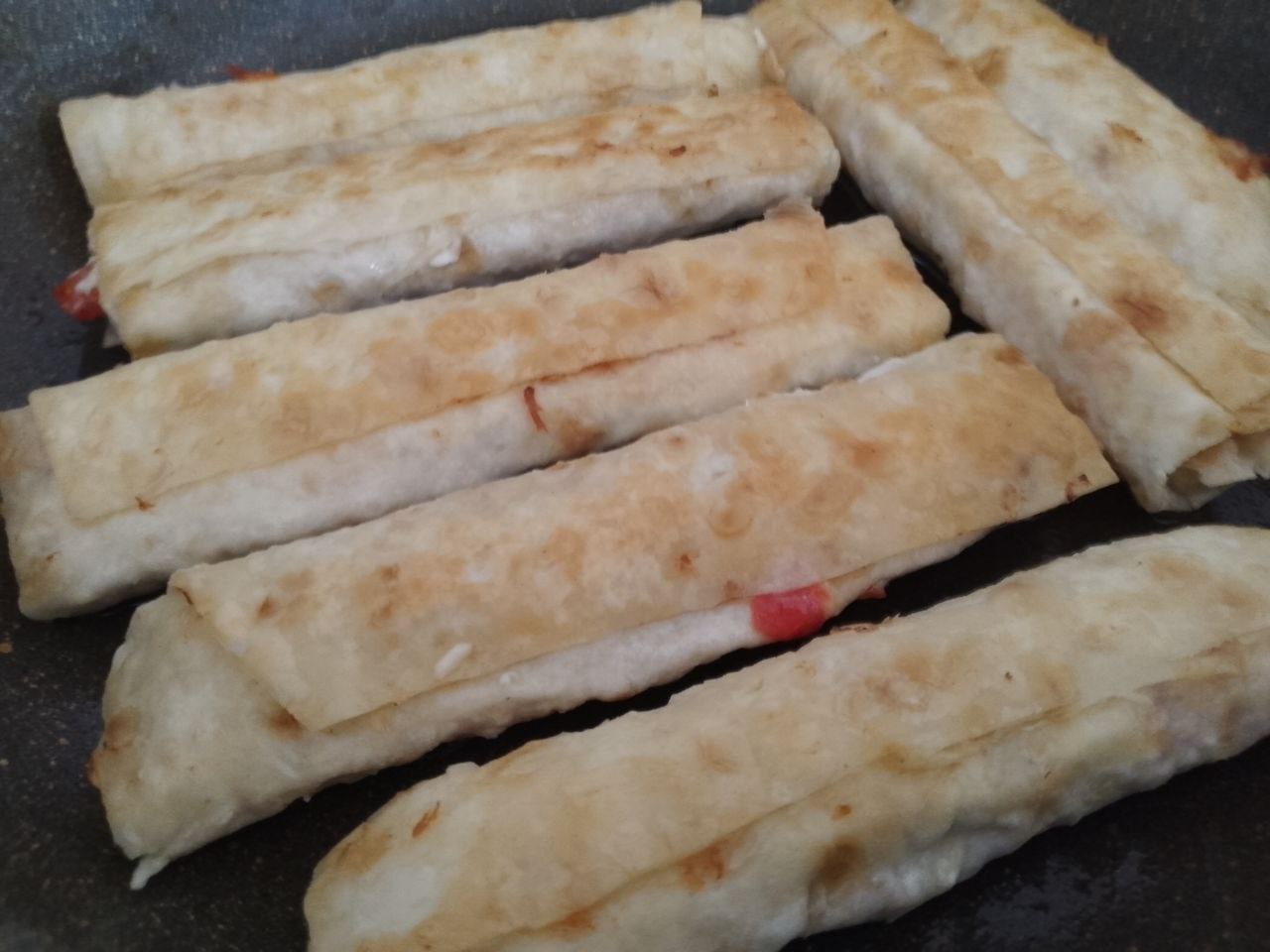 Лаваш с начинкой из куриного мяса, сыра и помидоров: Разогреваем сковороду с растительным маслом и обжариваем рулетики с двух сторон.