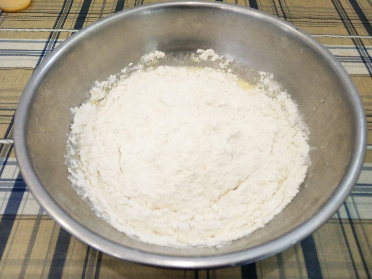 Булочки воздушные и слоистые, с крошкой: Муку просеиваем через мелкое сито и частями добавляем в смесь, замешиваем мягкое и нежное тесто.
