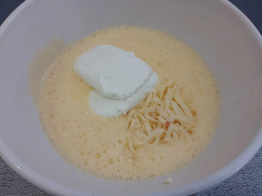 Вкусный завтрак из яиц, творога, помидоров и колбасы или ветчины: Соединяем взбитые яйца творог, тертый сыр и измельченный чеснок.