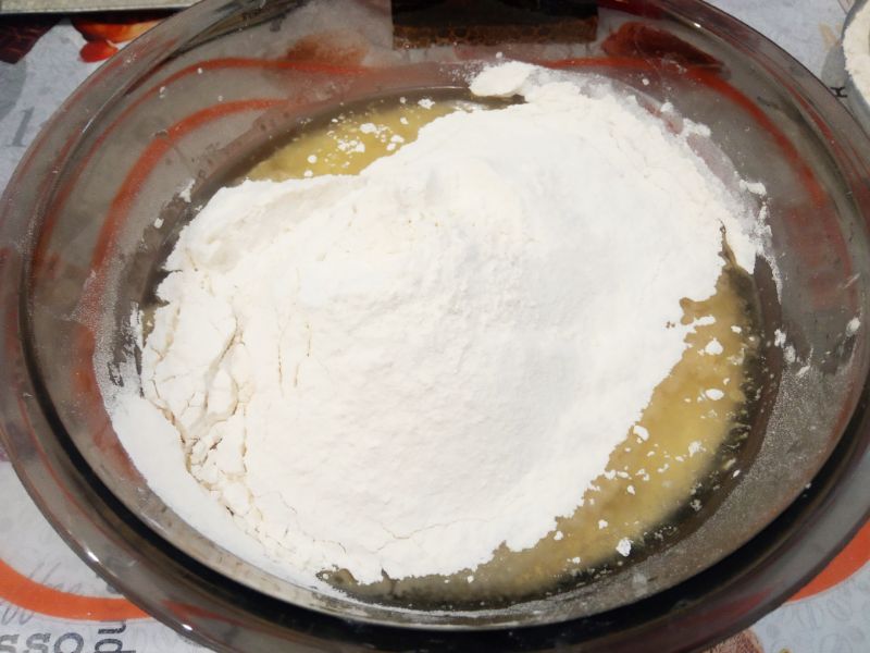 Домашние батоны с кунжутом на сыворотке, просто и вкусно: Добавляем половину муки, размешиваем лопаткой или ложкой.