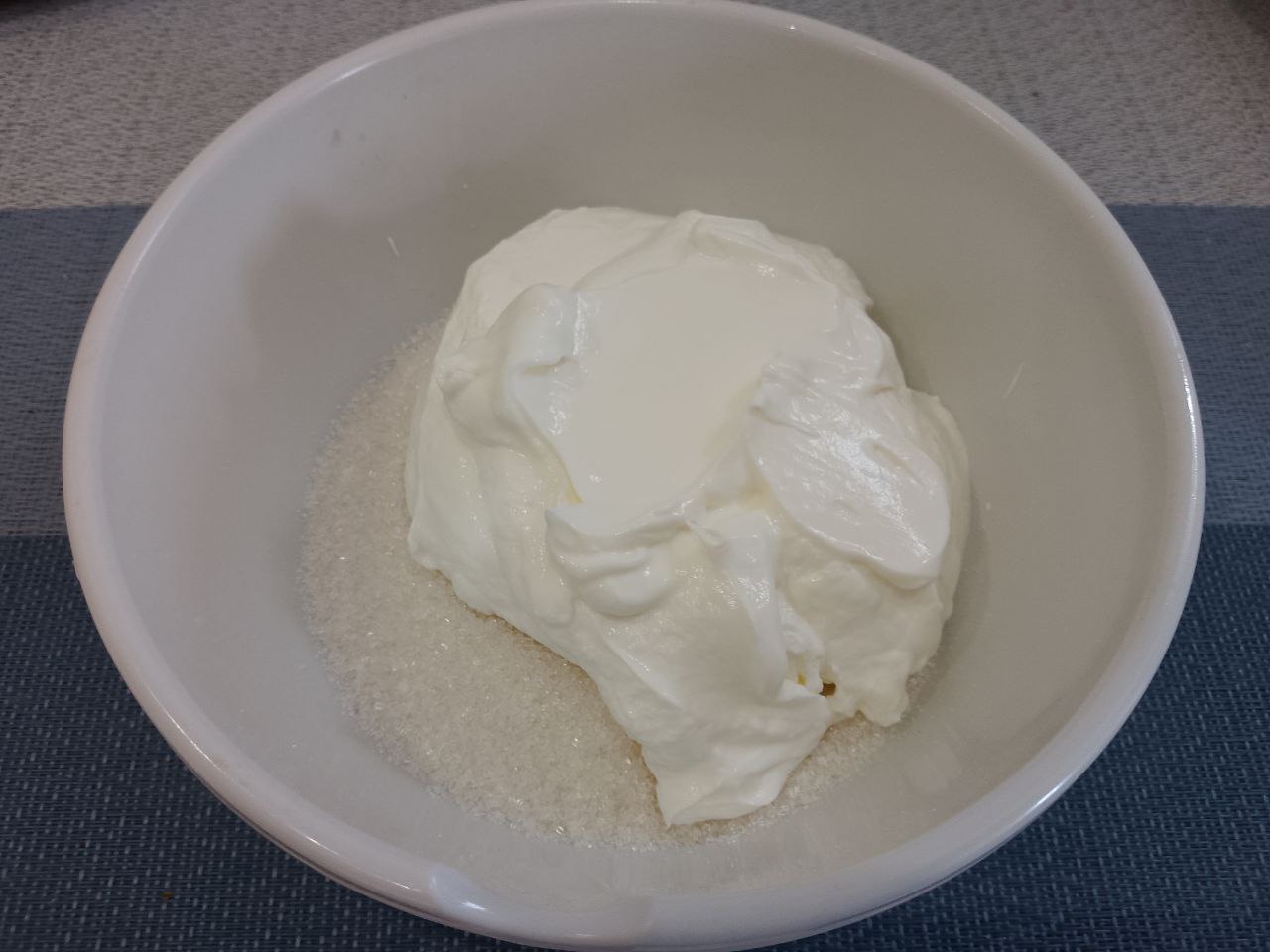Десерт из творога, изюма и кураги, нежный и вкусный: В чашу насыпаем сахар (по своему вкусу), добавляем ванилин и сметану, взбиваем до исчезновения сахара.