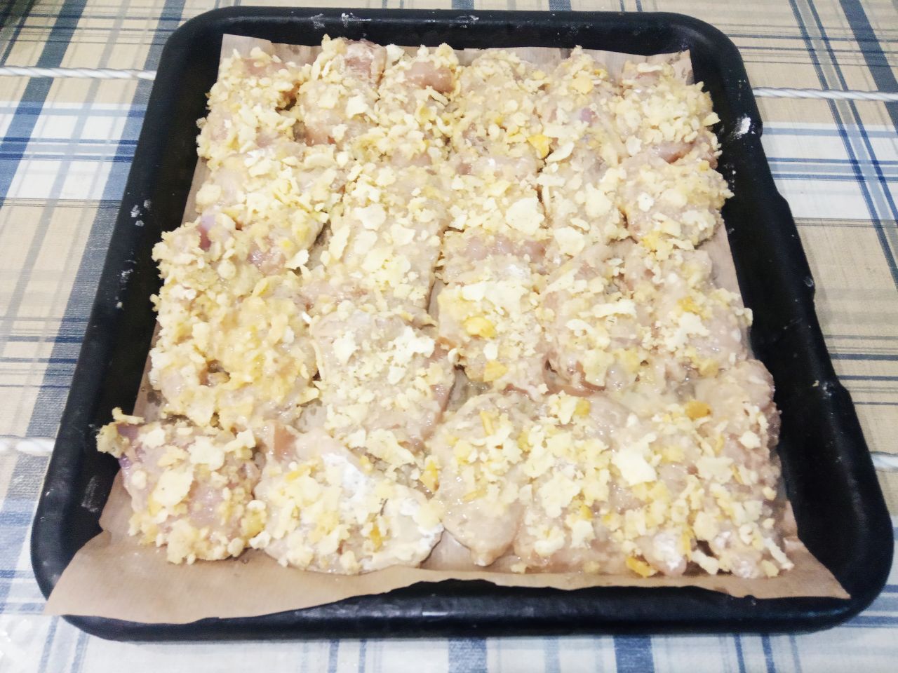 Запеченные куриные полоски в кляре и чипсах, нежные и сочные: Противень застилаем пергаментом, пергамент смазываем жиром и укладываем полоски.