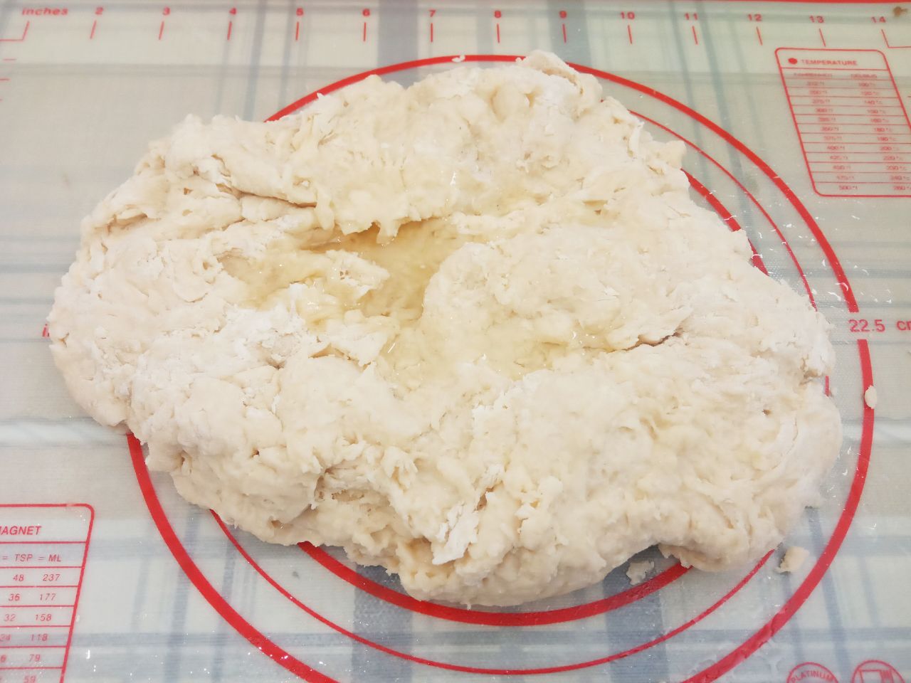 Воздушные треугольники, просто и вкусно: Выкладываем тесто на рабочую поверхность, смазанную маслом и сверху поливаем маслом.Замешиваем мягкое и