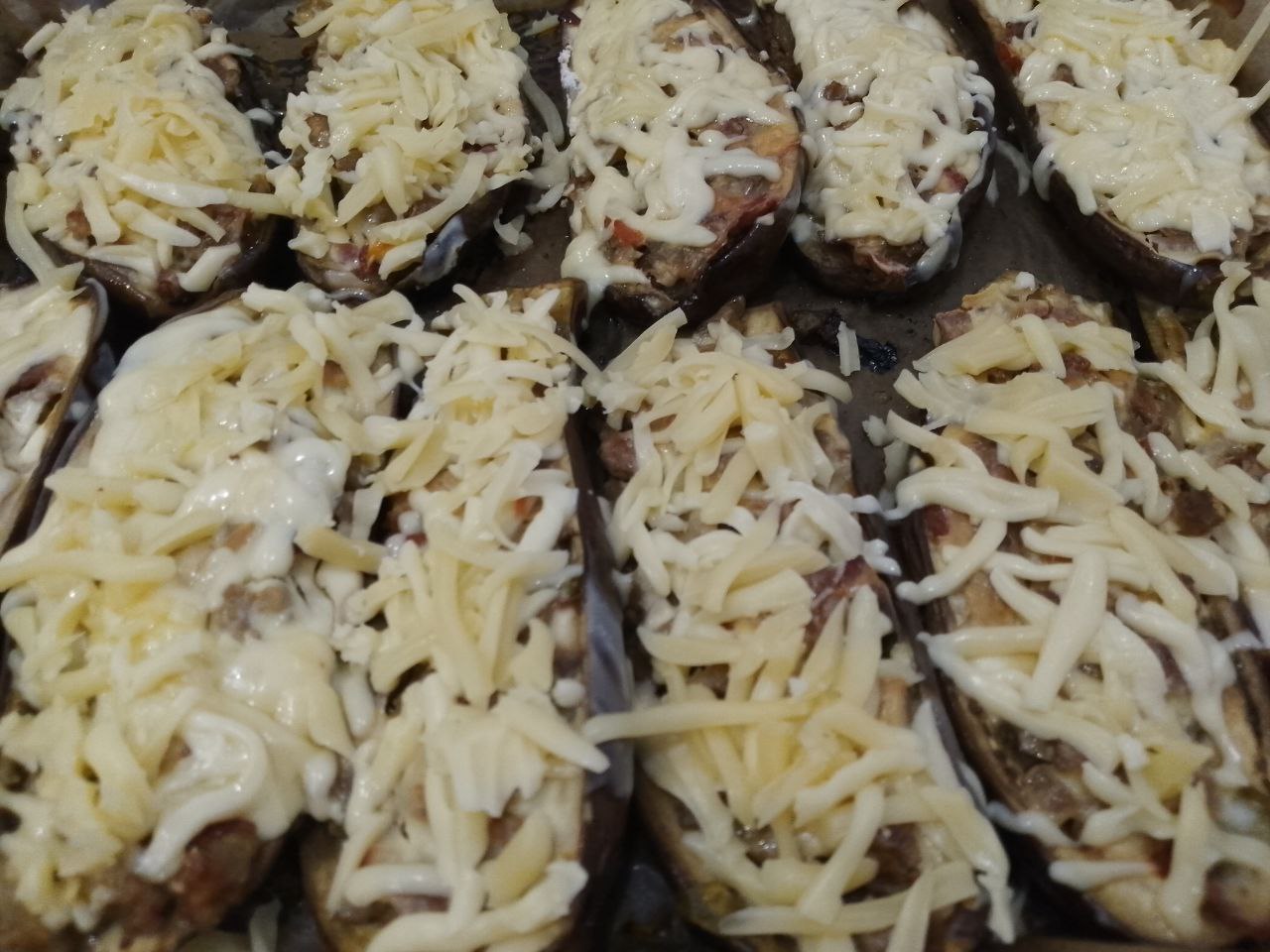 Запеченные в духовке, баклажаны с овощами, фаршем и сыром: Достаем баклажаны из духовки и посыпаем тертым сыром. Ставим баклажаны с начинкой в духовку, чтобы растаял