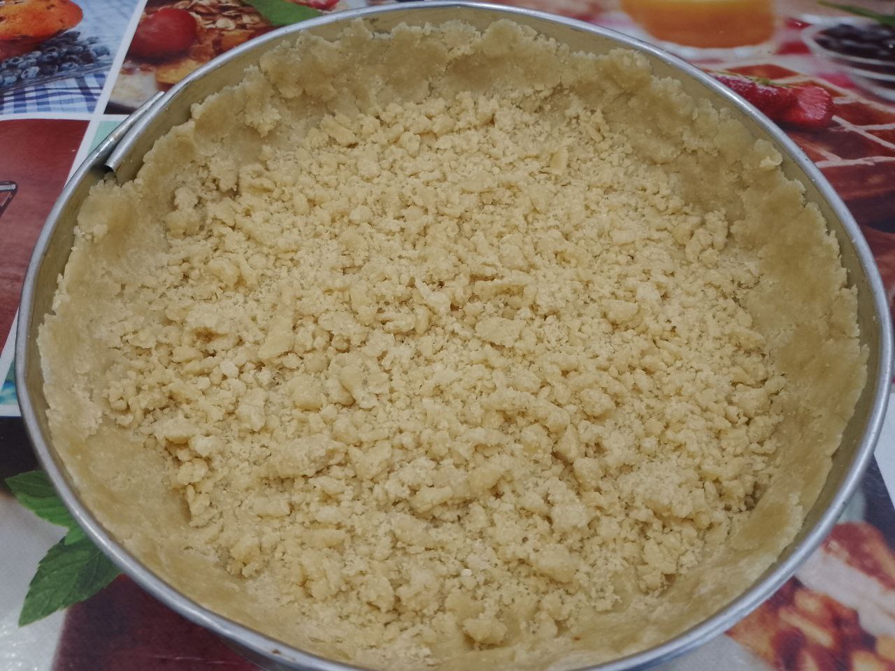 Пирог из песочной крошки, творожной начинки и ягод клубники: Форму застилаем пергаментом и большую часть крошки выкладываем на дно формы и формируем высокие бортики по