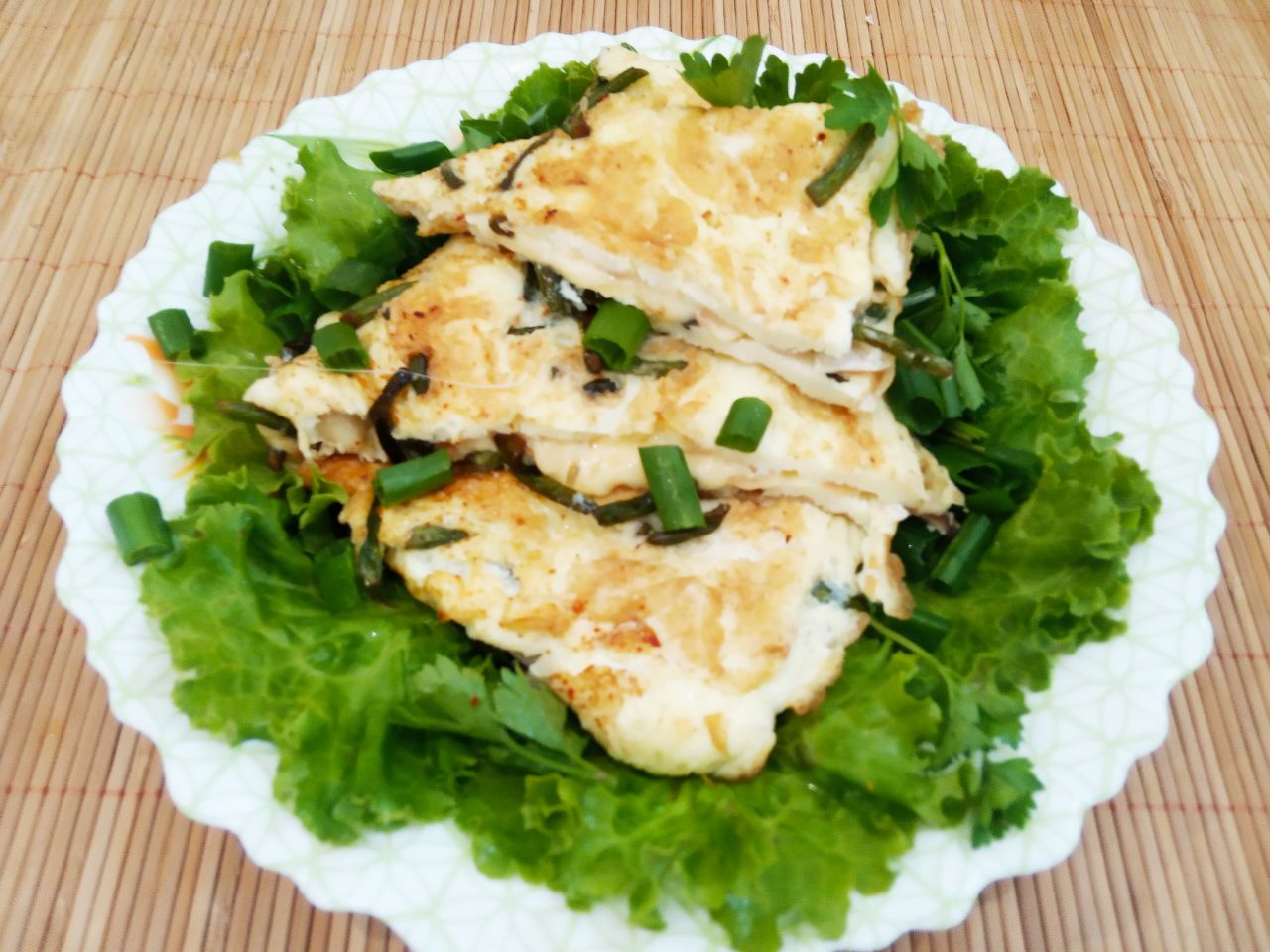 Вкусный и аппетитный завтрак из омлета, чесночных стрелок и сыра: Выкладываем омлет на зелень салата, сверху посыпаем измельченной зеленью и подаем к завтраку.