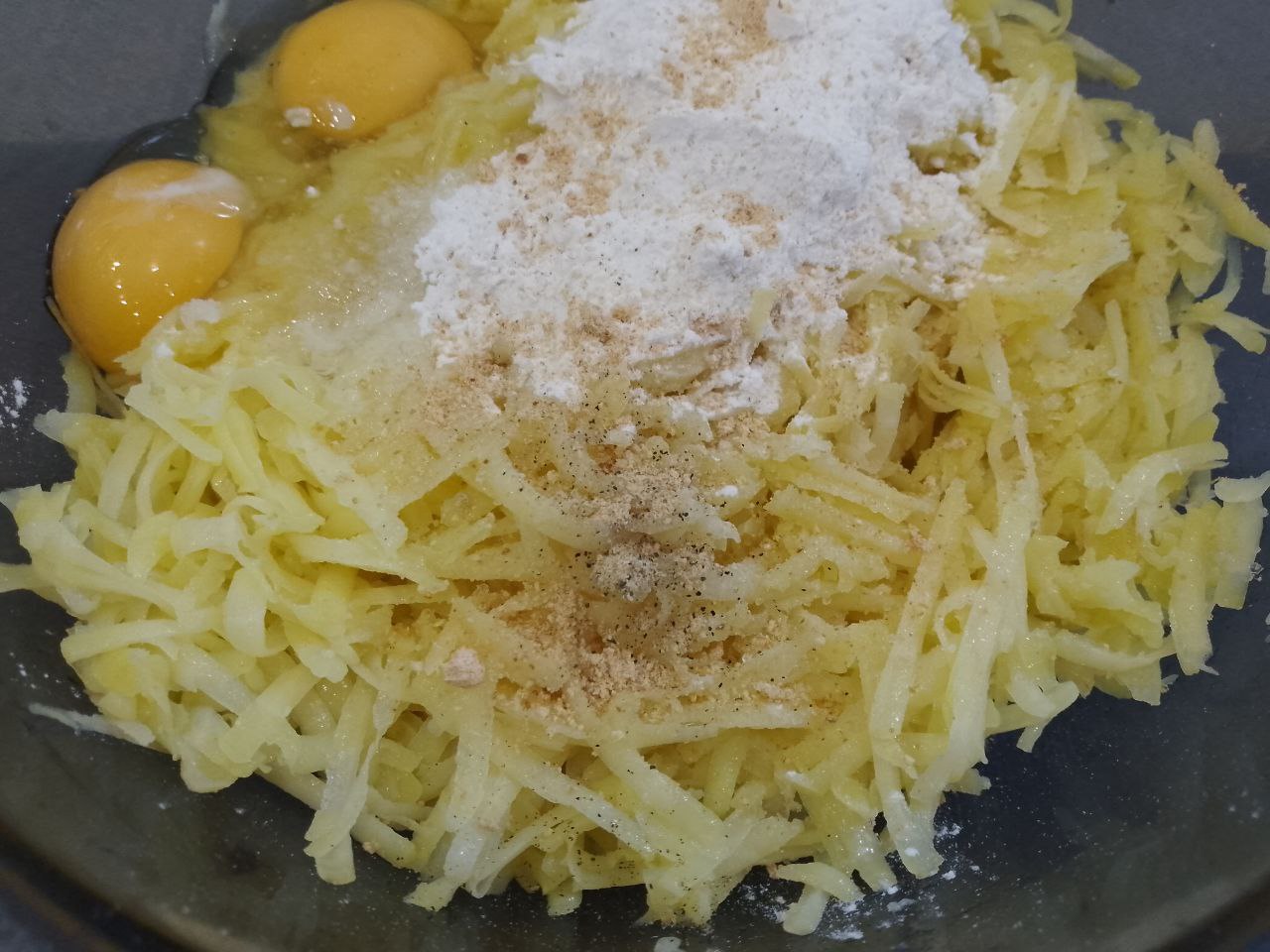 Рулет из тертого картофеля с мясной начинкой, запеченный в духовке: В тертый картофель добавляем муку, яйца, соль, перец и чеснок, тщательно размешиваем.
