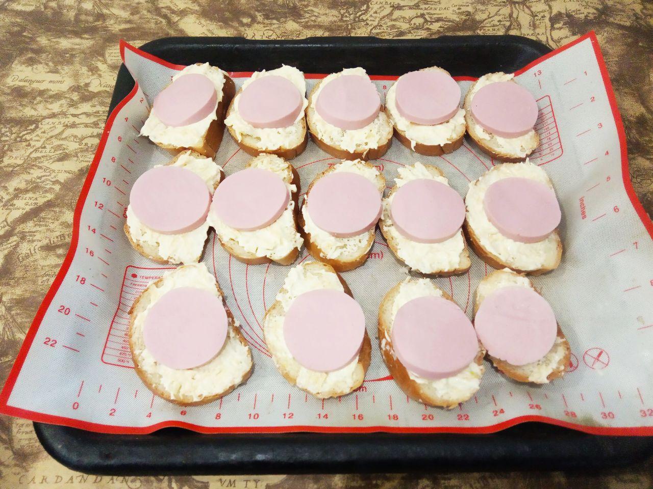 Вкусные и аппетитные горячие бутерброды с сыром и помидорами: Сверху на сырную пасту кладем ломтики колбасы.