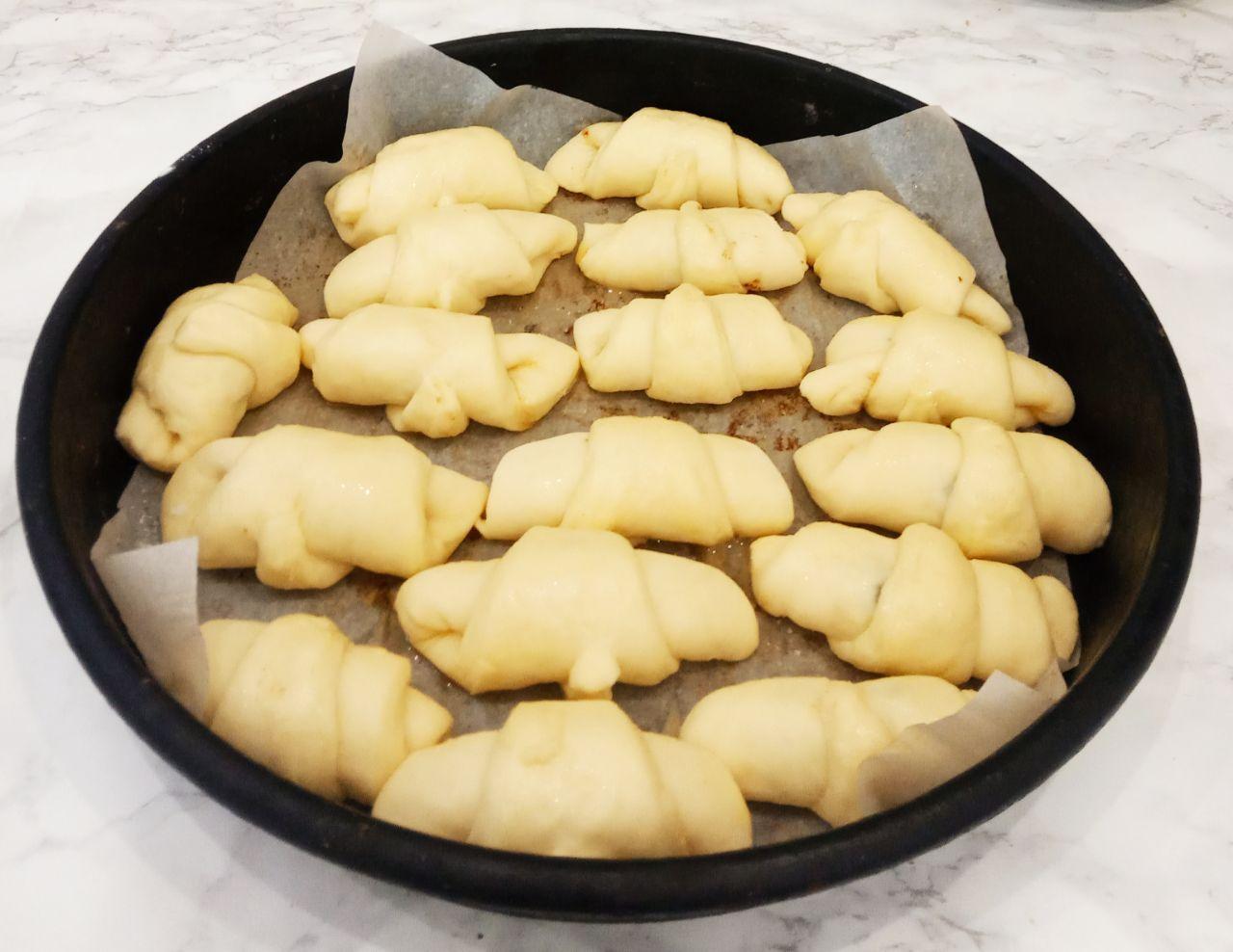 Воздушные и аппетитные рогалики с черносливом или курагой, просто и вкусно: Застилаем противень пекарской бумагой и укладываем рогалики и оставляем на 20 минут для расстойки теста.