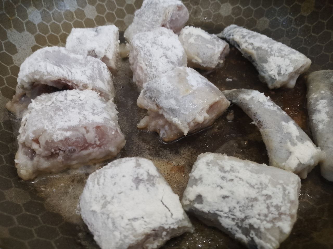 Рыба тушеная с овощами, в томатном соусе: Разогреваем сковороду с растительным маслом, обваливаем кусочки в муке и обжариваем с двух сторон до румяной