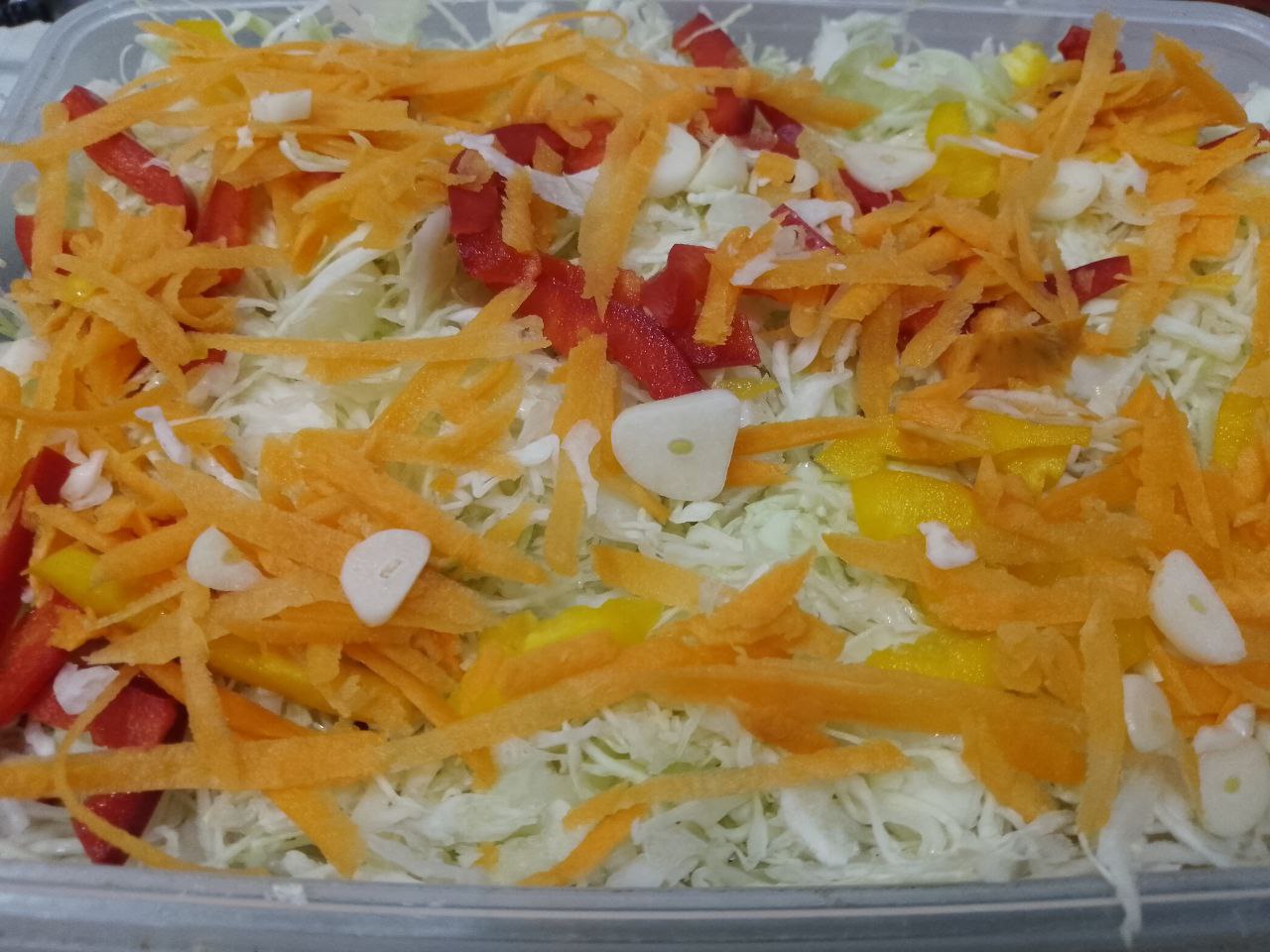 Капуста маринованная с перцем, морковью и чесноком: На перец выкладываем тертую морковь и ломтики чеснока. Так чередуем несколько слоев, верхний слой перца,