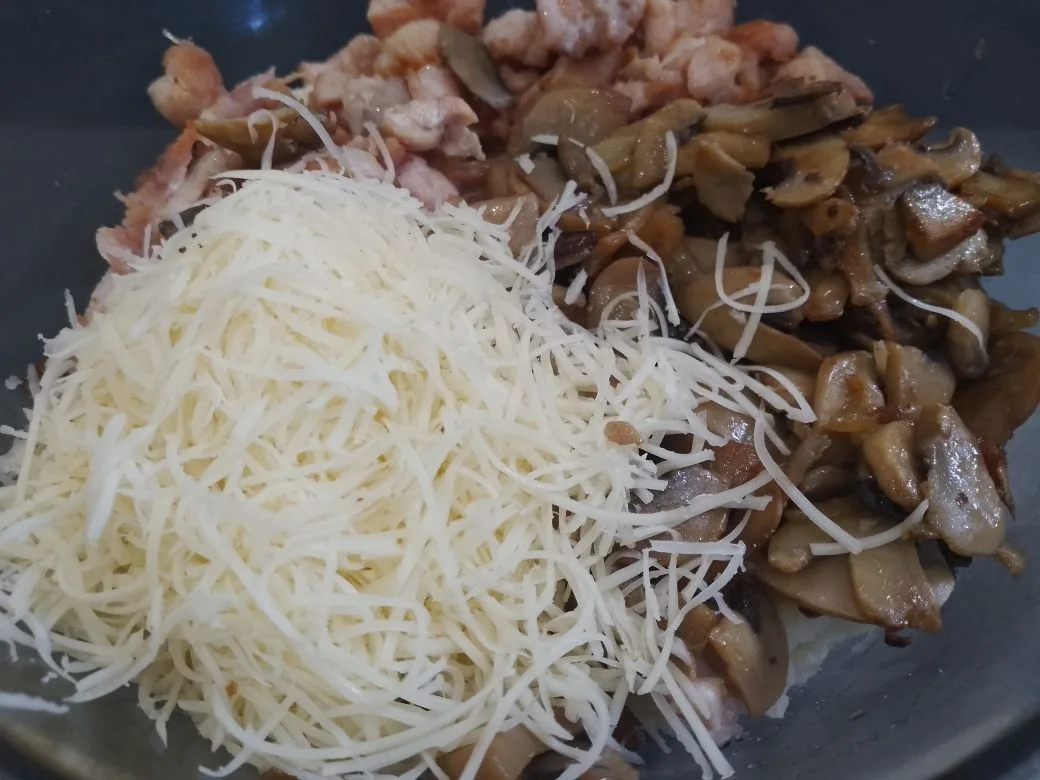 Картофель с начинкой из куриного мяса, шампиньонов и сыра: В миске картофель разминаем, добавляем шампиньоны, куриное мясо и половину твердого сыра, перемешиваем.