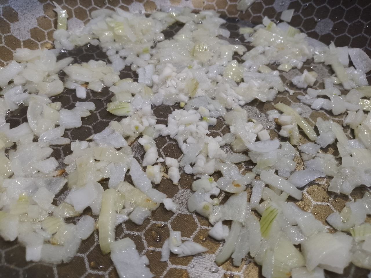 Макаронная запеканка с курицей, сыром и помидорами: Разогреваем сковороду с растительным маслом, обжариваем лук с чесноком до золотистого цвета.