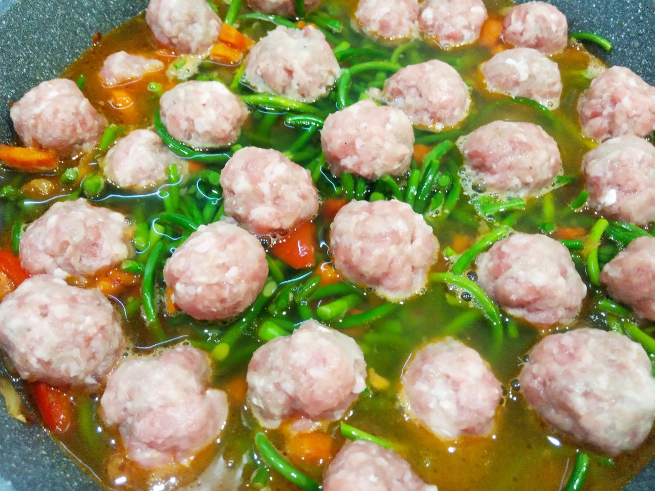 Чесночные стрелки с овощами, томатным соусом и мясным фаршем: Кладем к овощам чесночные стрелки, мясные шарики, соль и перец по вкусу, заливаем горячей кипяченой водой,