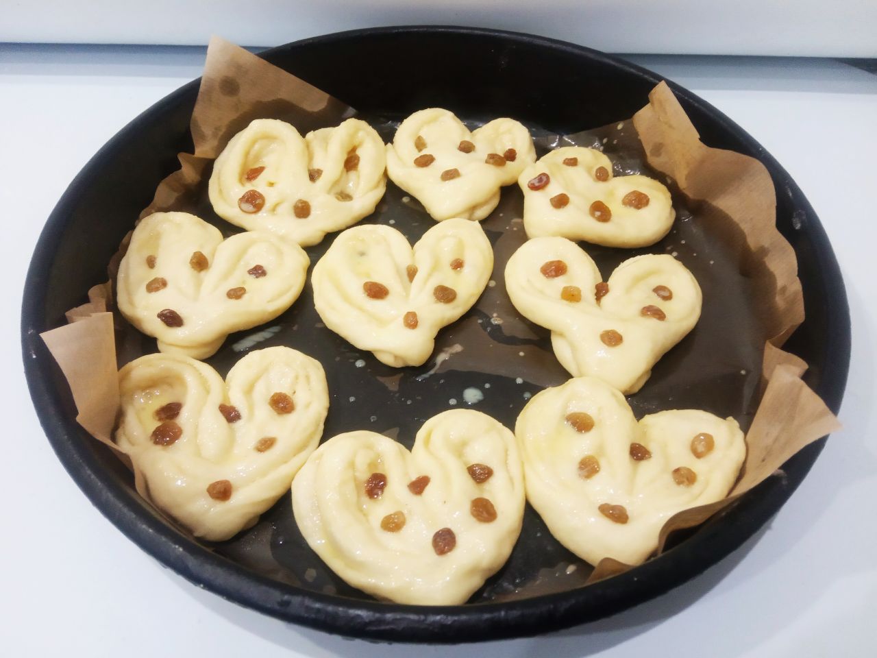 Сахарные булочки к чаю, просто и вкусно: Противень застилаем пергаментом и укладываем булочки. На половину булочек сверху выкладываем изюм. Булочки