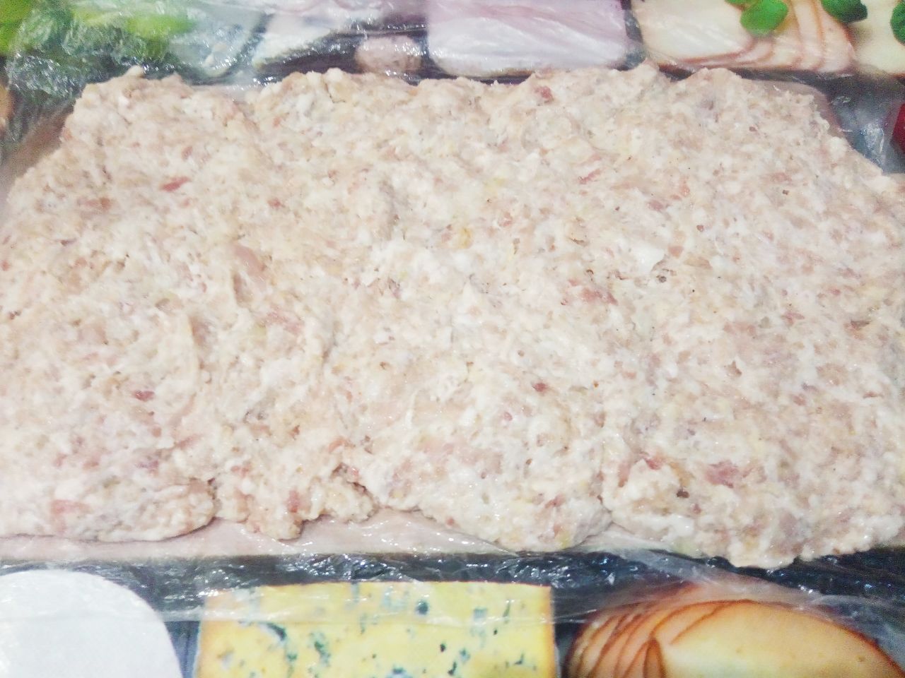 Мясной рулет с начинкой из грибов и жареного лука: Пленку смазываем растительным маслом и выкладываем равномерно фарш небольшим слоем.