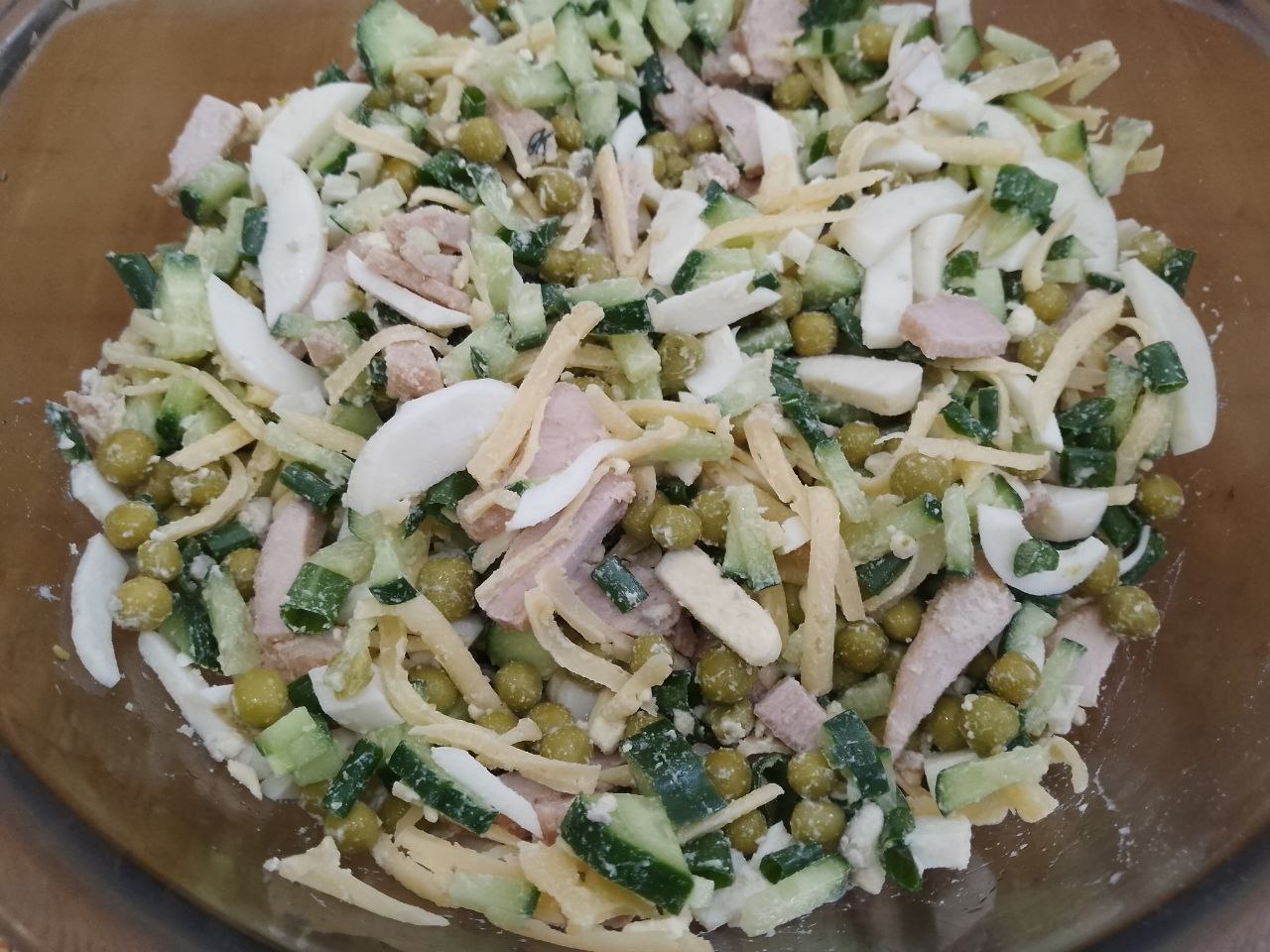 Салат с мясом, зеленым горошком и сухариками: В чаше соединяем мясо, сыр, зеленый горошек, зеленый лук, огурцы и яйца, перемешиваем.