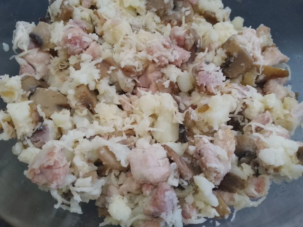 Картофель с начинкой из куриного мяса, шампиньонов и сыра: В миске картофель разминаем, добавляем шампиньоны, куриное мясо и половину твердого сыра, перемешиваем.