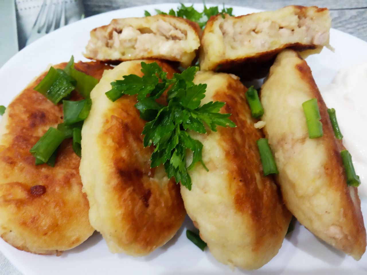 Картофельные пирожки с начинкой из куриного филе и лука: Обжаренные пирожки складываем на блюдо, посыпаем зеленью и подаем со сметаной или с соусом по желанию.