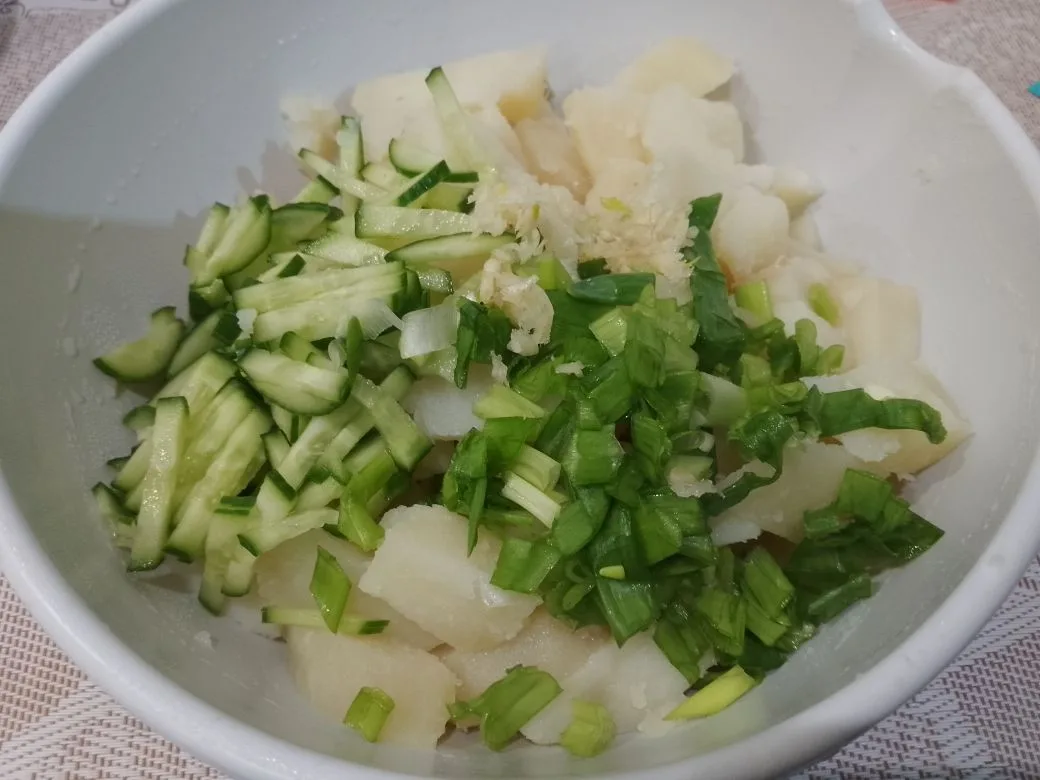 Картофель с зеленым луком, чесноком и свежим огурцом: Добавляем в миску с картофелем измельченный лук, огурцы и чеснок.