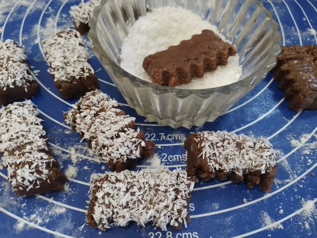 Шоколадное песочное печенье с кунжутом и кокосовой стружкой: Одну часть полосок смазываем и обваливаем в кунжуте, вторую в кокосовой стружке.