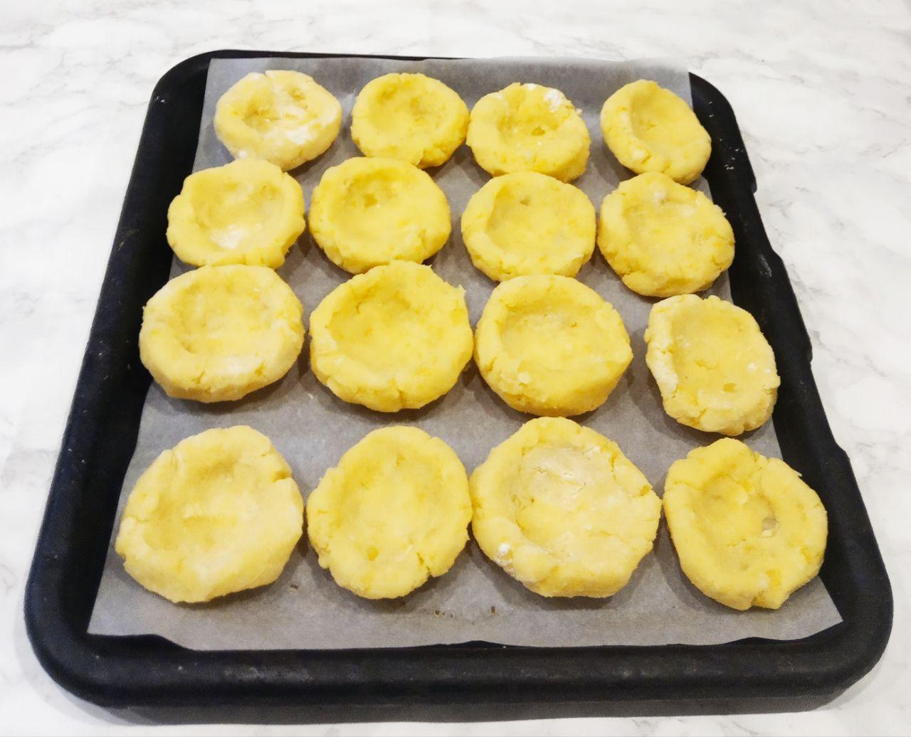 Картофельные ватрушки с мясной начинкой и сыром: Противень застилаем пергаментом, а с теста формуем ватрушки с углублением для начинки.