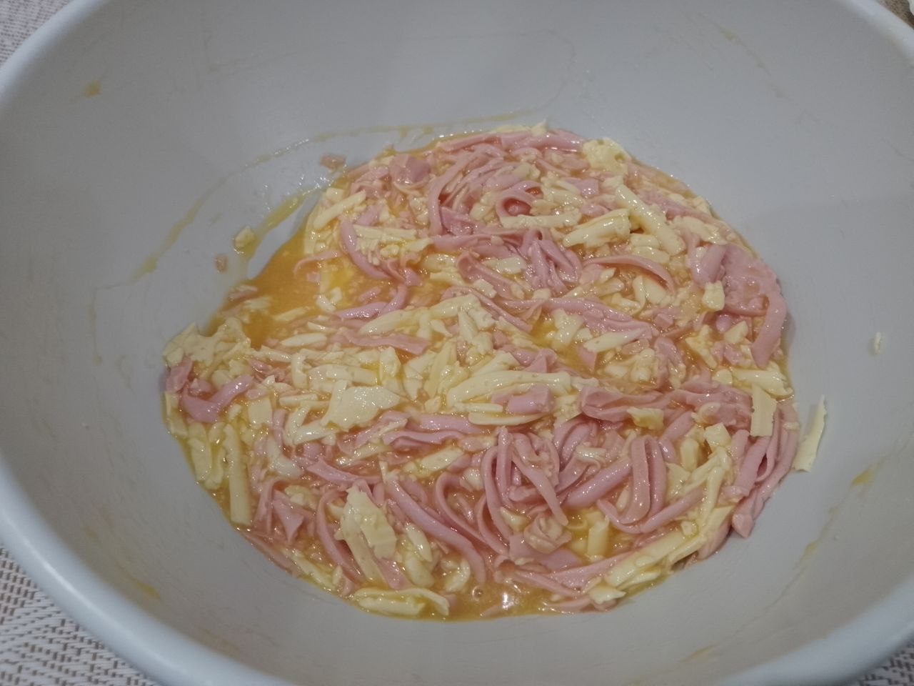 Бутерброды с яйцами и сыром, жареные на сковороде: Делим смесь пополам, в одну добавляем колбасу и перемешиваем.