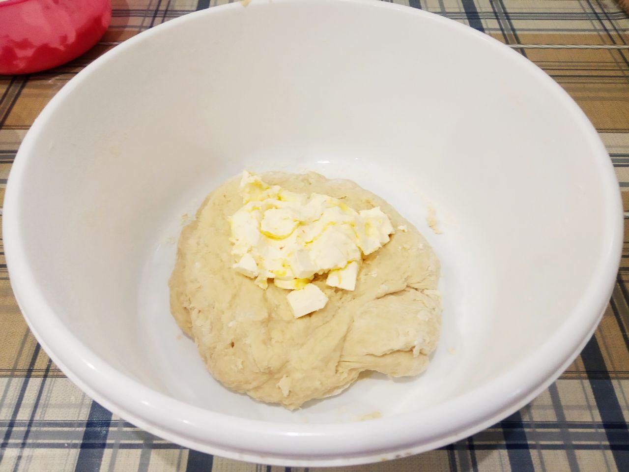 Жареные пончики без яиц с начинкой и с кунжутом: Размягченное сливочное масло кусочками кладем в середину теста и вымешиваем до нежного теста.