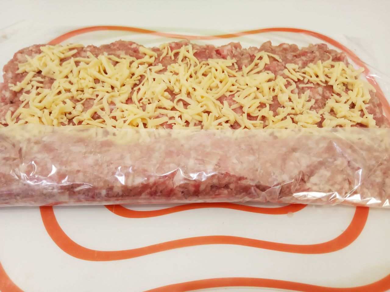 Мясной рулет с сыром в кляре, жареный на сковороде: Затем с помощью пленки сворачиваем котлетную массу рулетом.