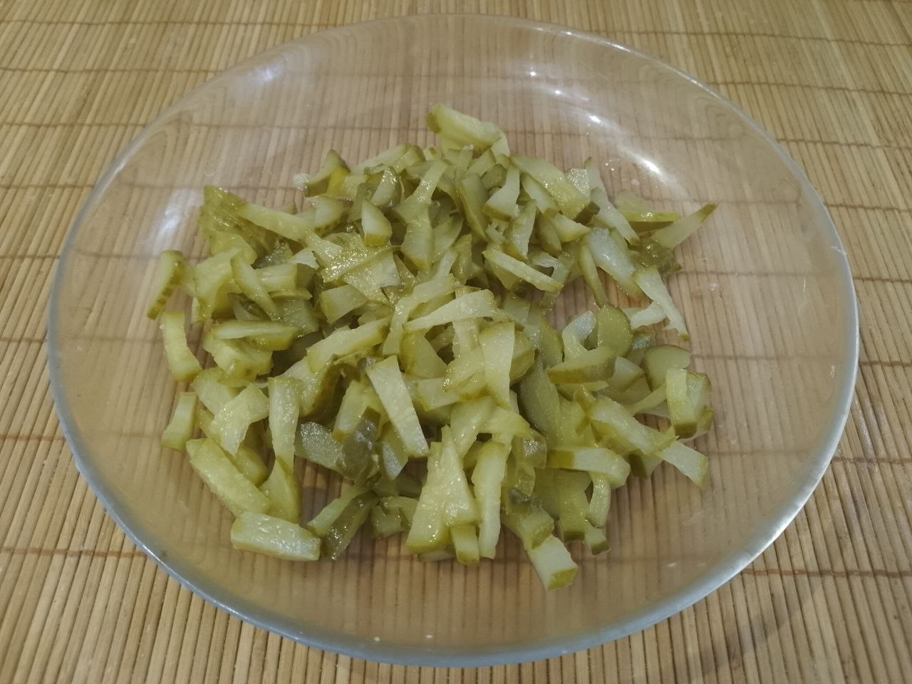 Сытный, вкусный и аппетитный салат из яичных блинов, ветчины и других ингредиентов: Консервированные или соленые огурцы нарезаем также тонкой соломкой.