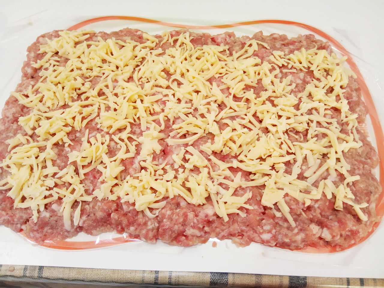 Мясной рулет с сыром в кляре, жареный на сковороде: Твердый сыр натираем на крупной терке и выкладываем на котлетную массу.