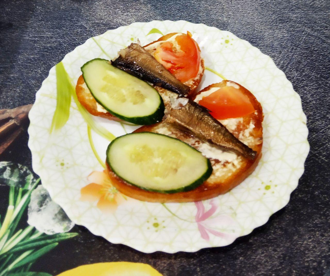 Аппетитные гренки со шпротами, огурцами и помидорами, просто и вкусно: Поверх майонеза кладем огурец, шпроту и ломтик помидора, а сверху веточку зелени.