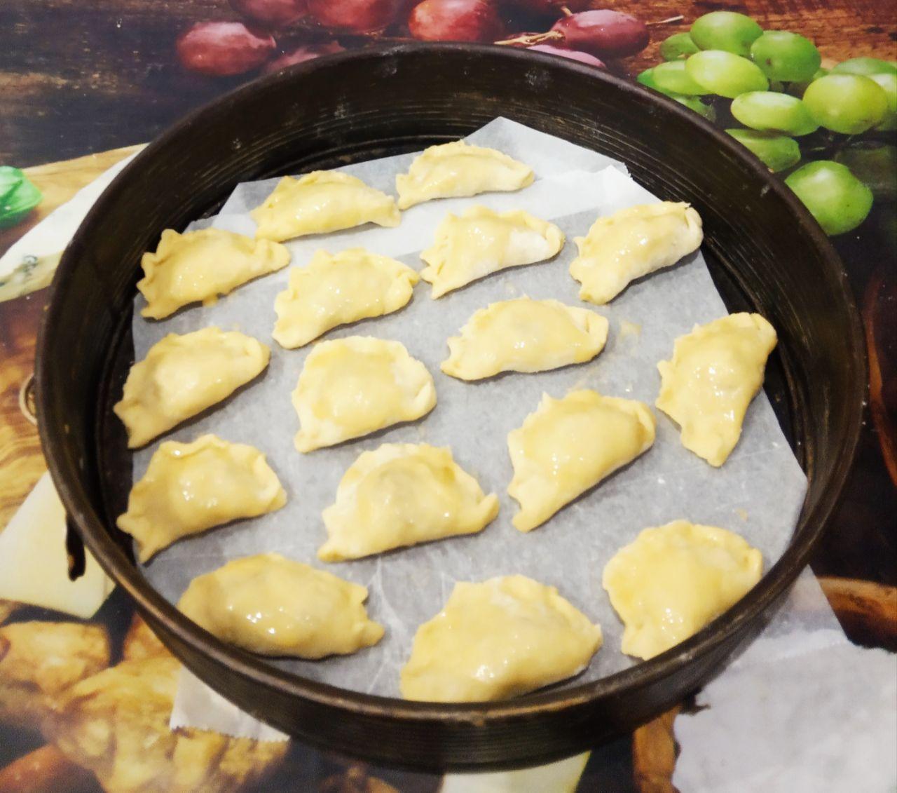 Вкусные пирожки с начинкой из тушеных яблок: Противень застилаем пергаментом и укладываем пирожки.