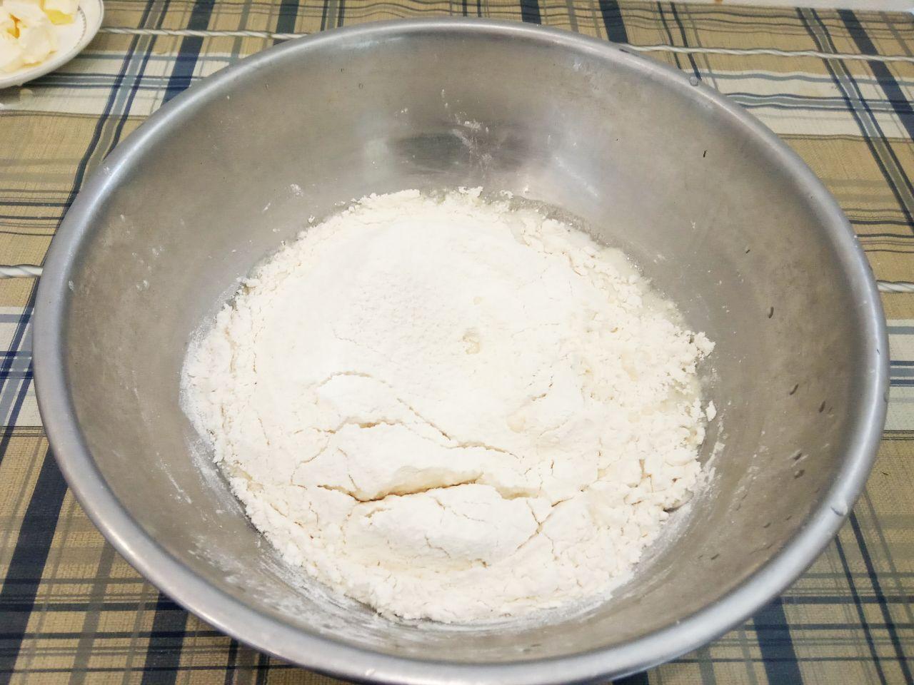 Булочки с шоколадной крошкой из дрожжевого теста на желтках: Муку просеиваем через мелкое сито и всыпаем половину муки в смесь, размешиваем.