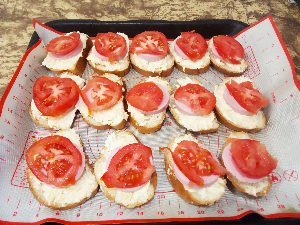 Вкусные и аппетитные горячие бутерброды с сыром и помидорами: На колбасу кладем ломтики помидор.
