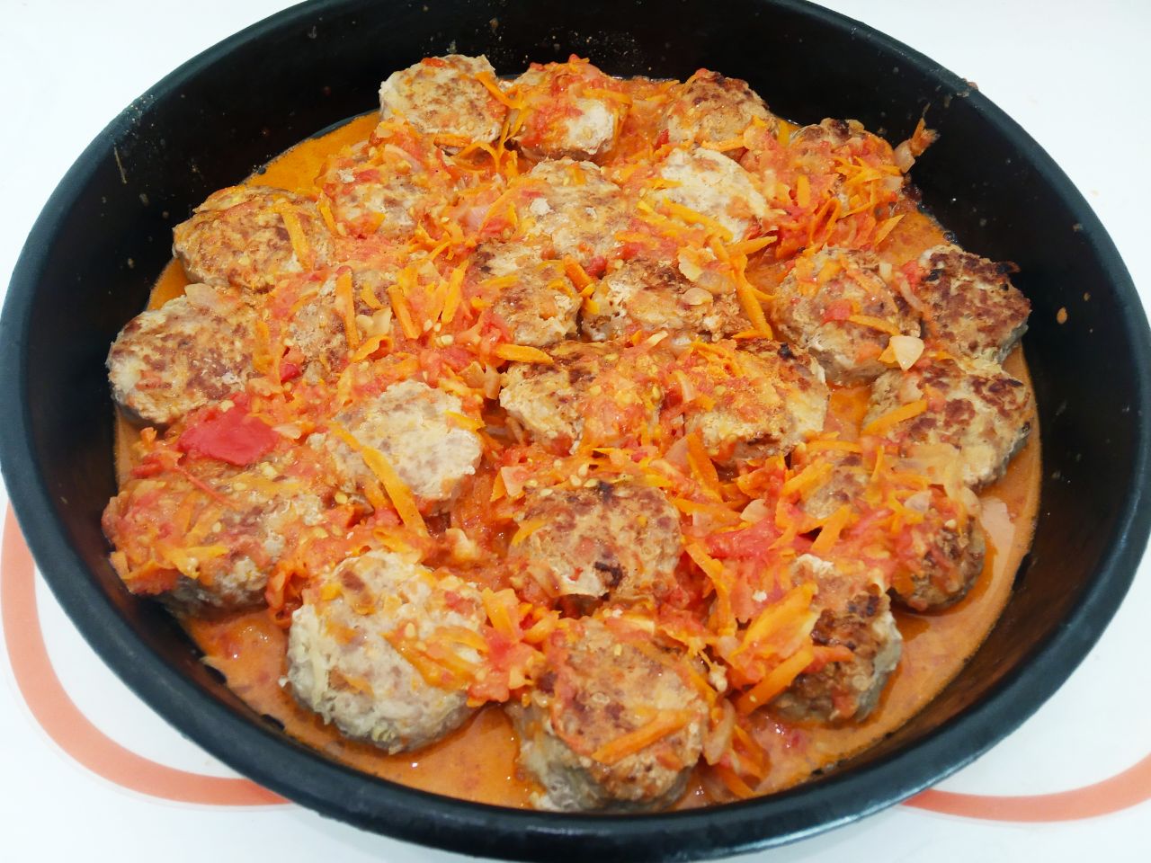 Капустные биточки с фаршем и соусом в духовке: Складываем биточки на противень и заливаем приготовленным соусом.
