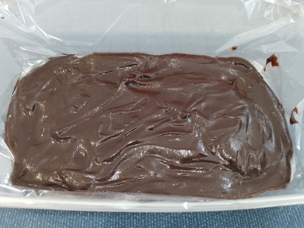Десерт из творога, изюма и кураги, в шоколадной глазури: Форму или контейнер застилаем пищевой пленкой.  Дно формы заполняем половиной массы шоколадной глазури и