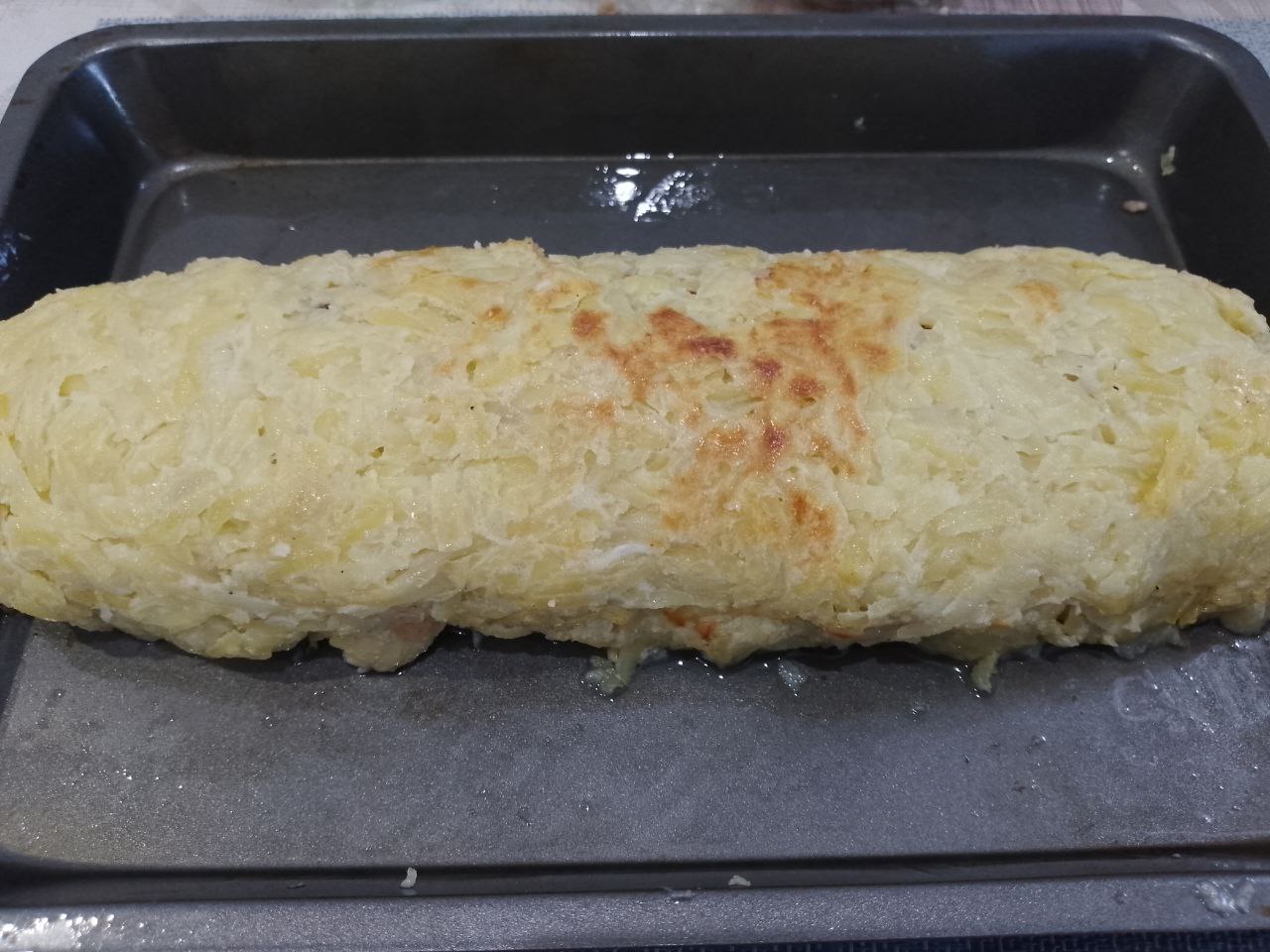 Рулет из тертого картофеля с мясной начинкой, запеченный в духовке: С помощью пергамента сворачиваем рулет и перекладываем в форму.
