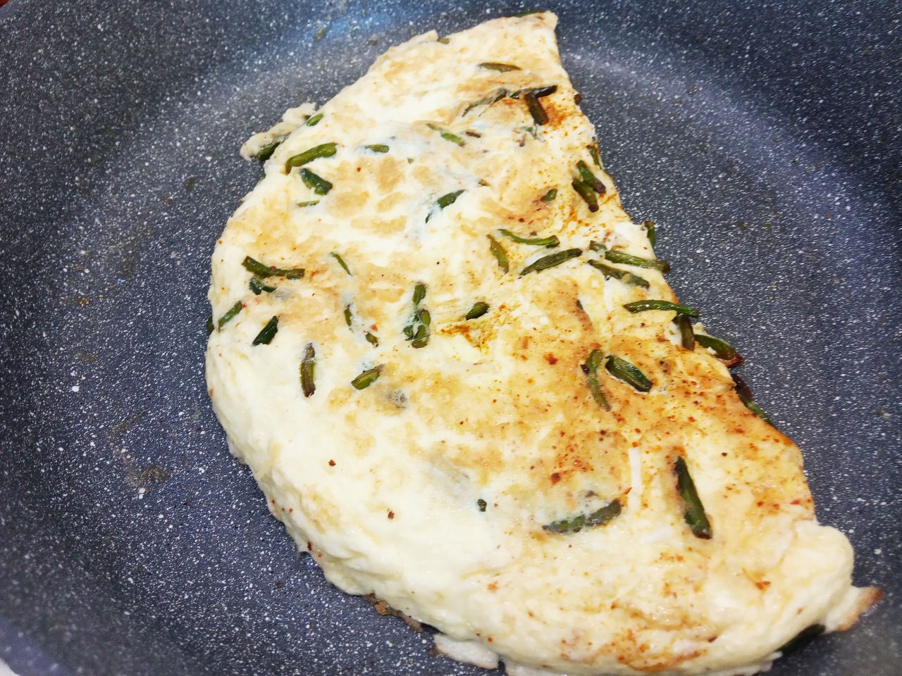 Вкусный и аппетитный завтрак из омлета, чесночных стрелок и сыра: Омлет посыпаем тертым сыром, сворачиваем вдвое и выдерживаем на сковороде пару минут.