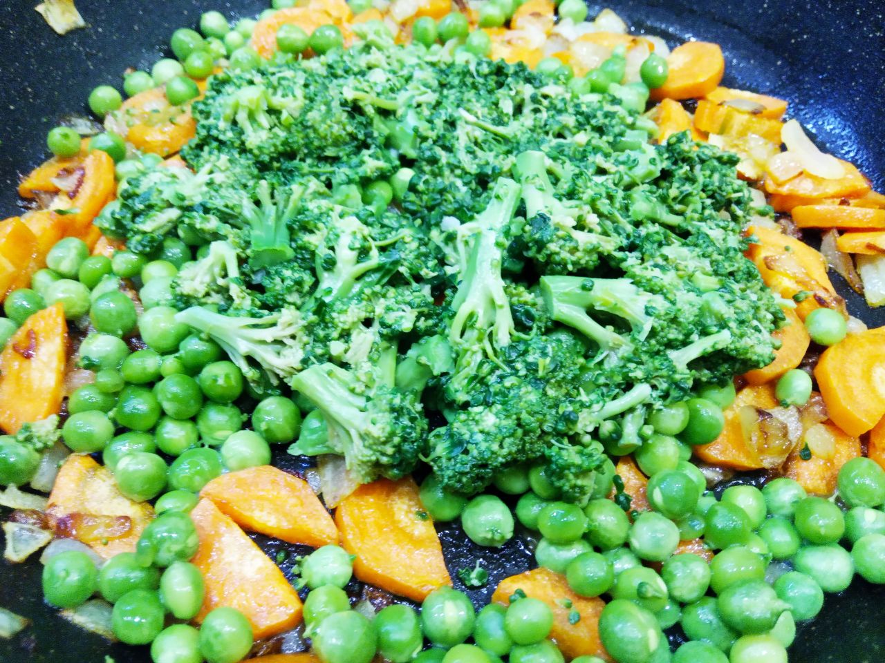 Тушеные овощи с рисом, брокколи и зелёным горошком, вкусно и полезно: Выкладываем к обжаренным луку с морковью, зеленый горошек и капусту.